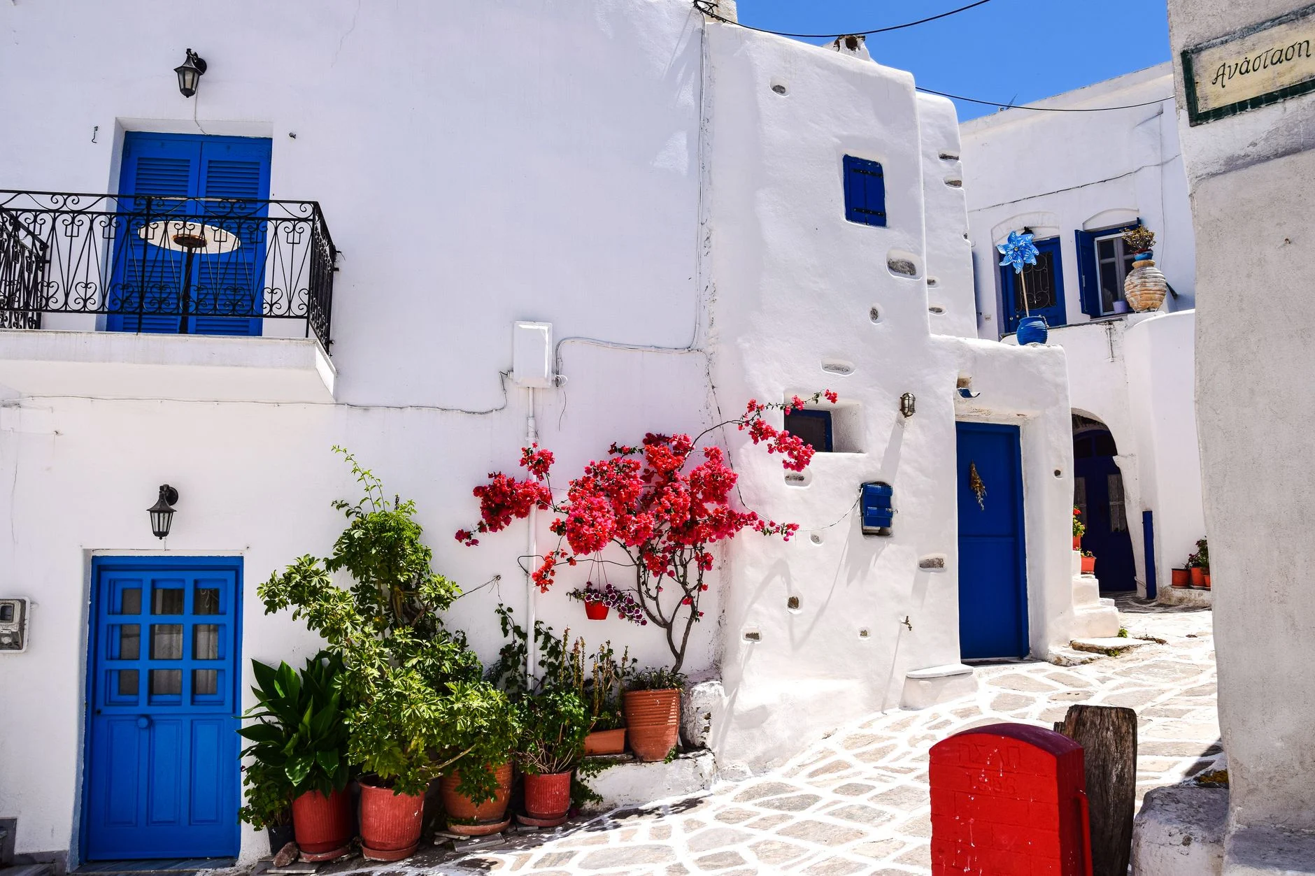 A white Cycladic alley with bougainvillea in the sun